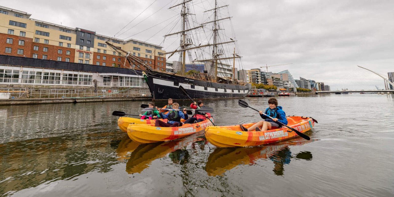 three kayaks in the liffey in dublin ireland beside jeanie johnston