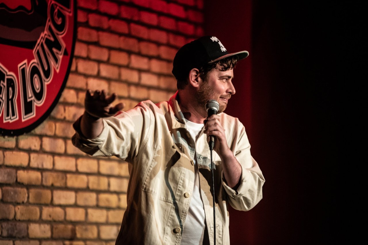 man on stage holding microphone with hand up